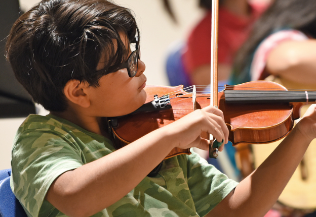 Young boy playing violin in group lesson