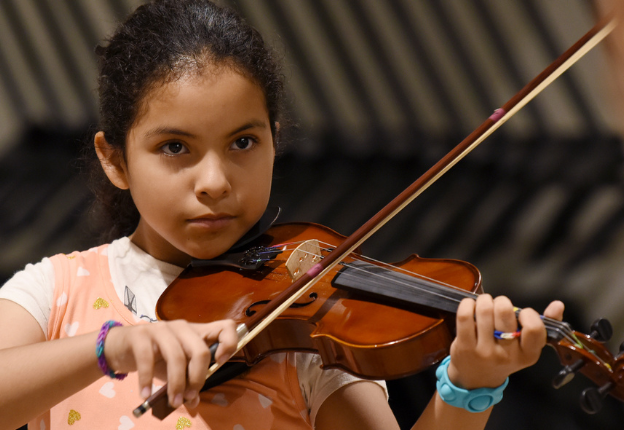 Focused young student playing violin in group lesson